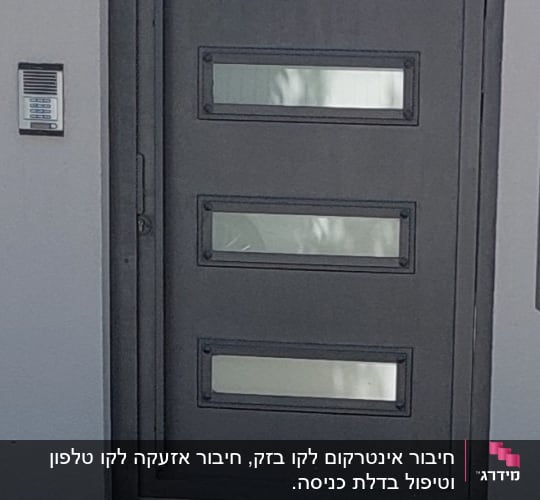 אינטרקום מותקן על קיר ליד שער מתכת אפור